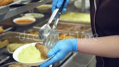 特写，食堂工作人员将一部分土豆泥放在盘子上.. 现代食堂、食堂、餐厅